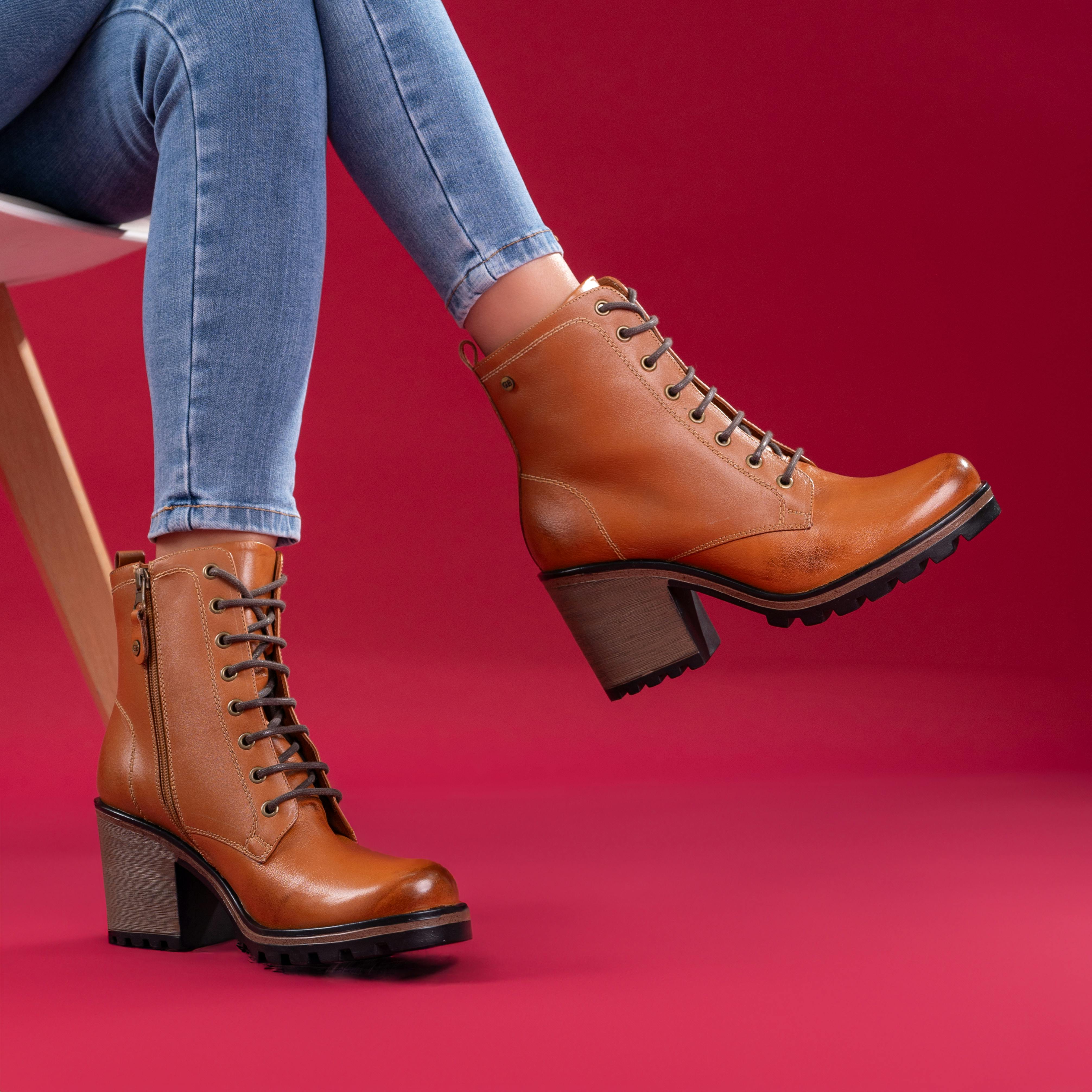 Fashionable brown boots paired with jeans in a vibrant red studio setting. Perfect for footwear styles.