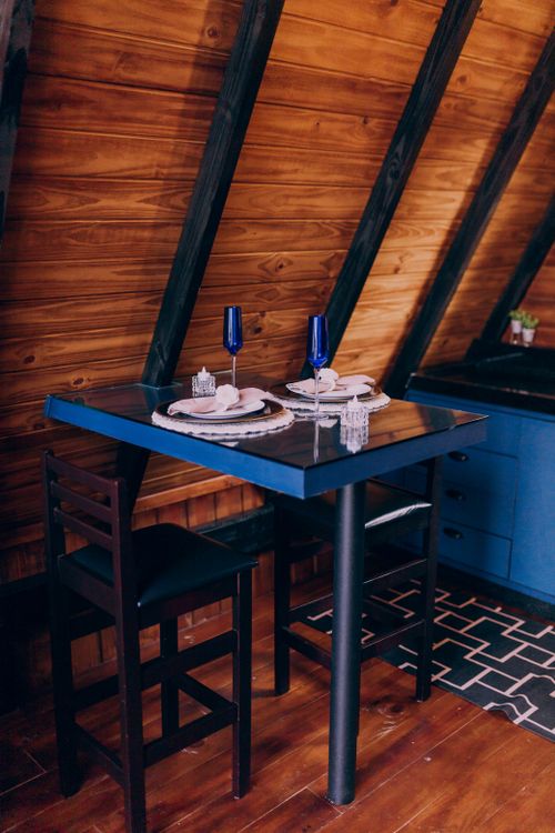 Free Stylish dining setup in a wooden A-frame cabin featuring modern blue elements and elegant tableware. Stock Photo