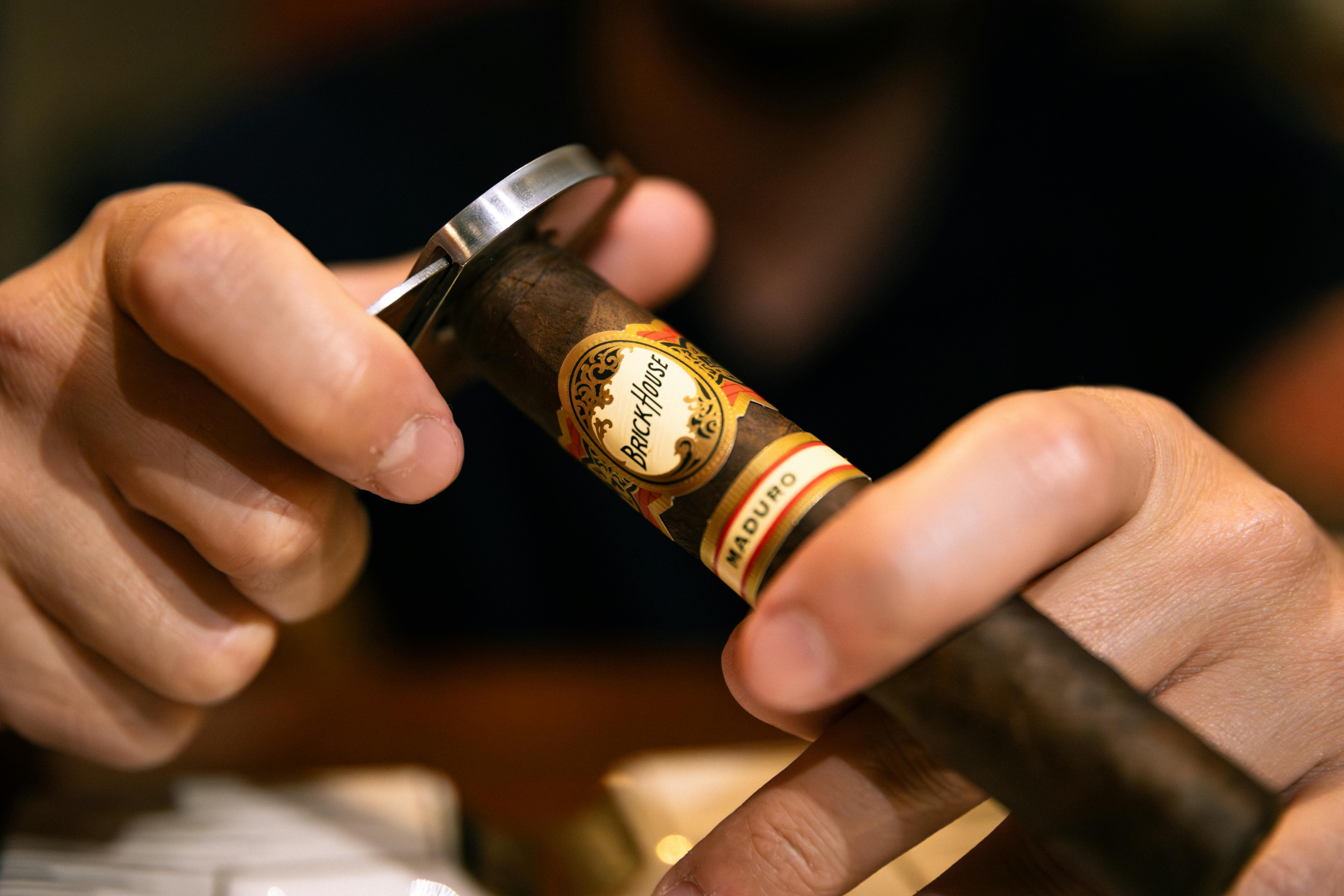 Close-up of a man using a cutter on a premium cigar for a precise smoking experience.