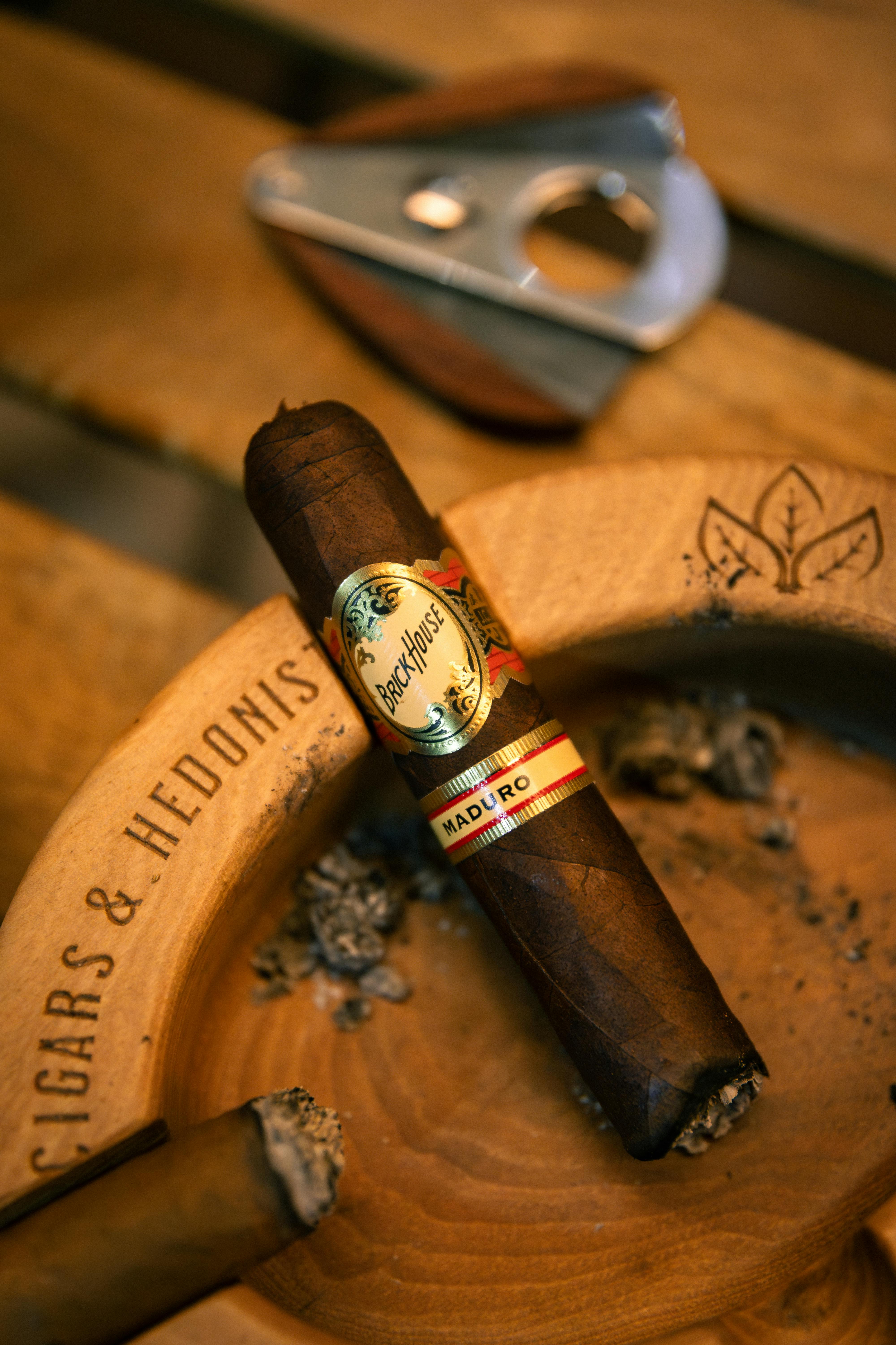 A luxury cigar rests on an ashtray with a cutter nearby, highlighting indulgence and sophistication.
