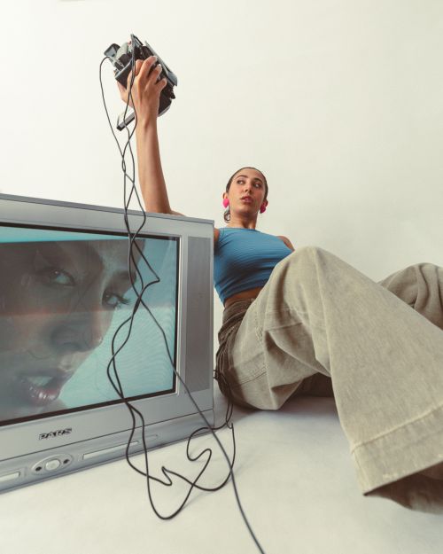 Free Stylish woman with vintage TV and camcorder in a modern setting. Stock Photo