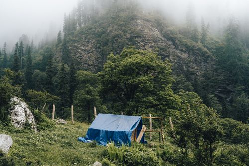 Free A serene blue tent in a misty mountain landscape surrounded by lush greenery. Stock Photo