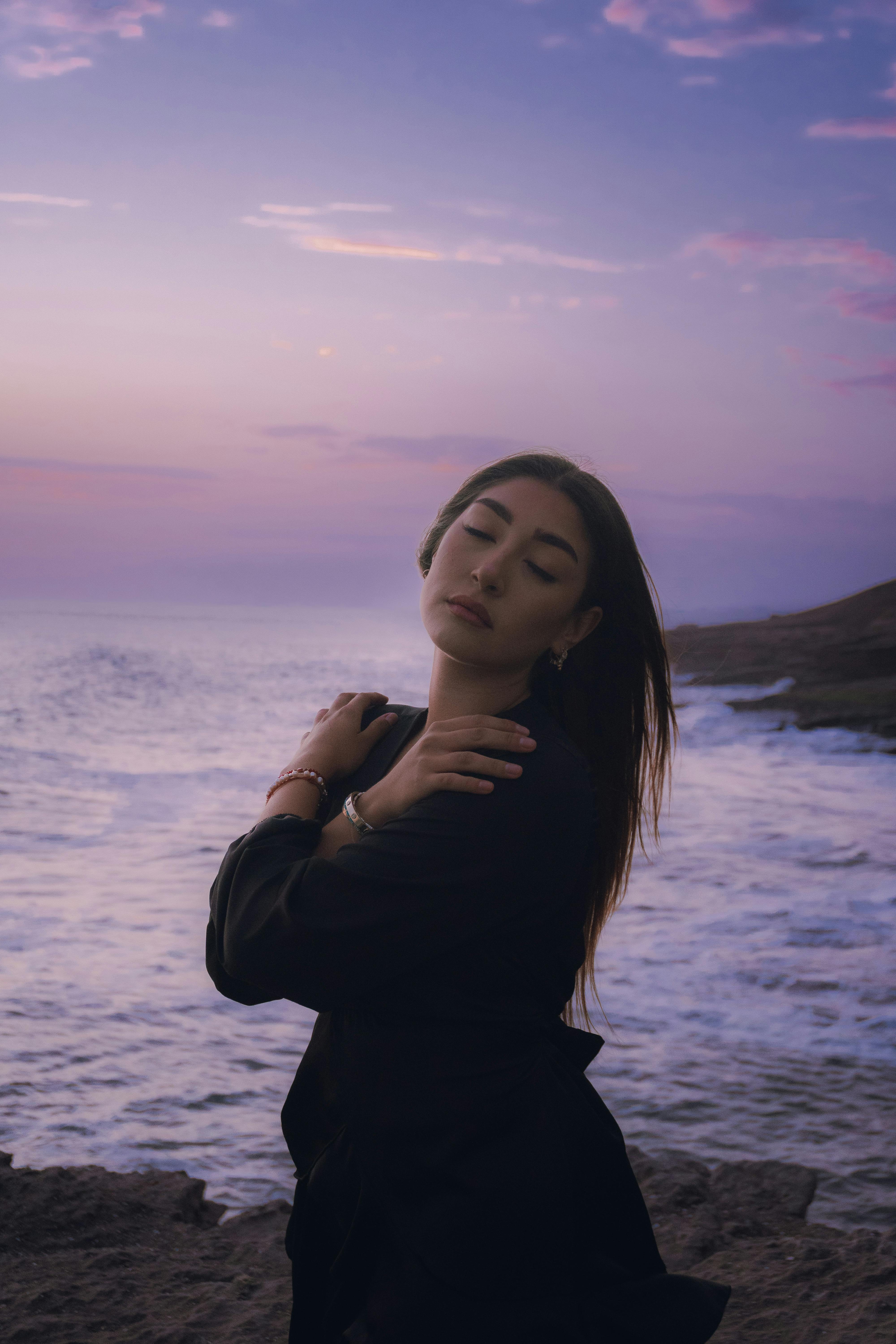 Captivating portrait of a woman embracing the tranquil ocean breeze during sunset in Callao, Peru.