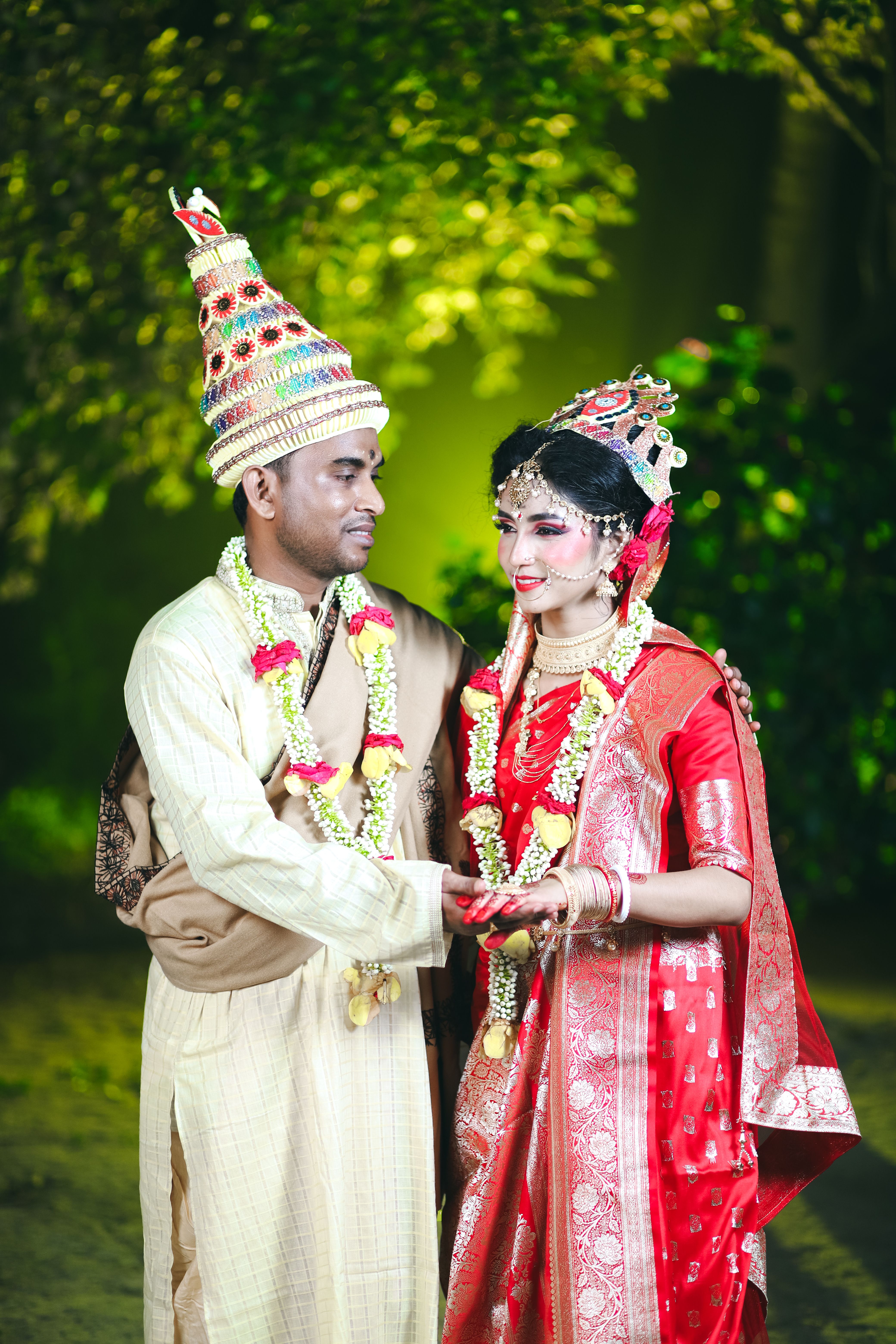 Beautiful portrait of a couple in traditional Indian wedding attire during an outdoor ceremony.