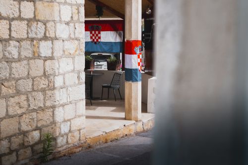 Free Close-up view of a Croatian flag displayed on a rustic stone house exterior, capturing tradition. Stock Photo