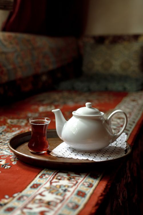 Free A white teapot with a tea glass on a decorative tray in a cozy setting. Stock Photo