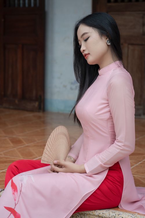 Free A young woman in a pink traditional dress elegantly holds a fan indoors, exuding serenity. Stock Photo