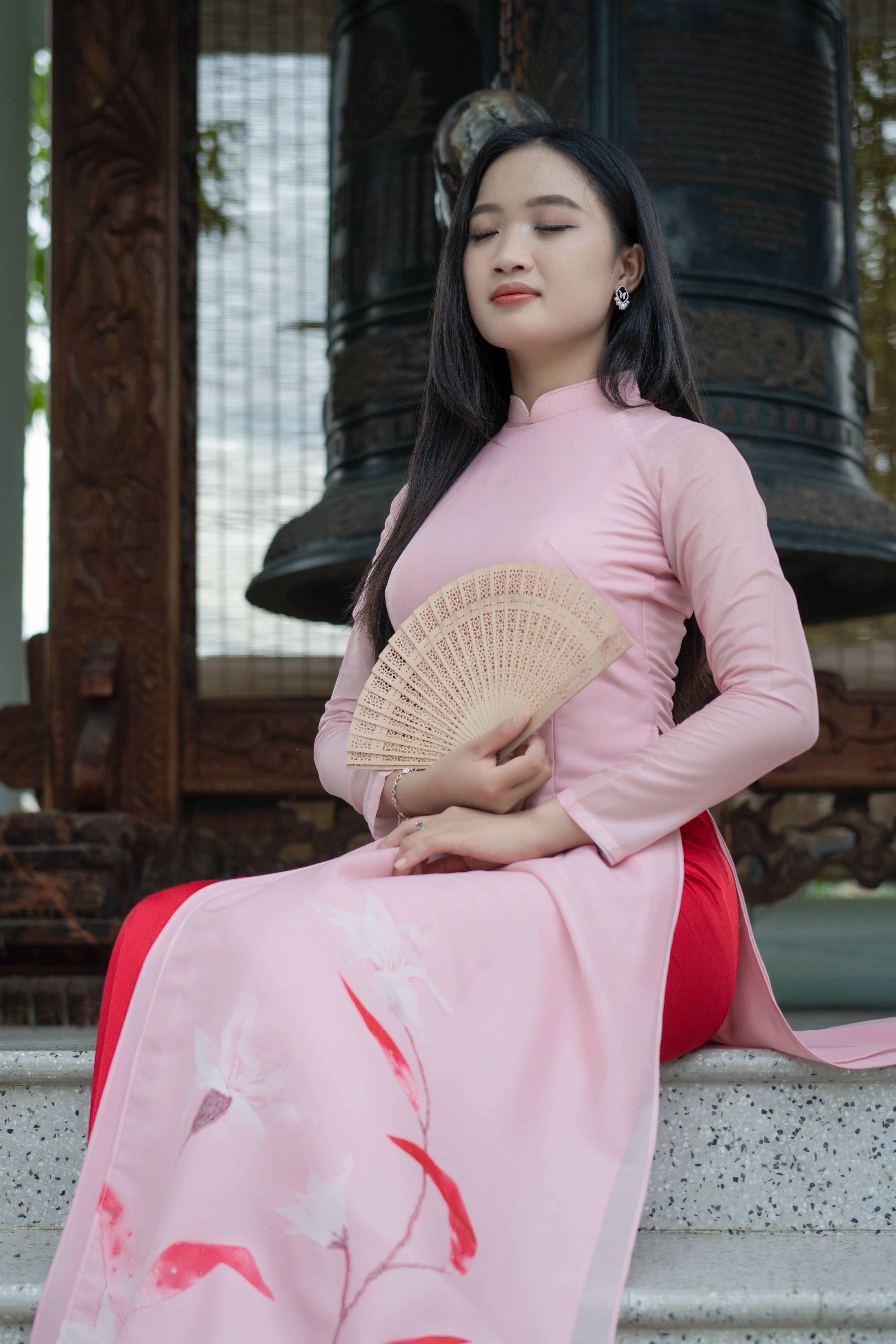 A woman in a pink dress sitting on a step with a fan · Free Stock Photo