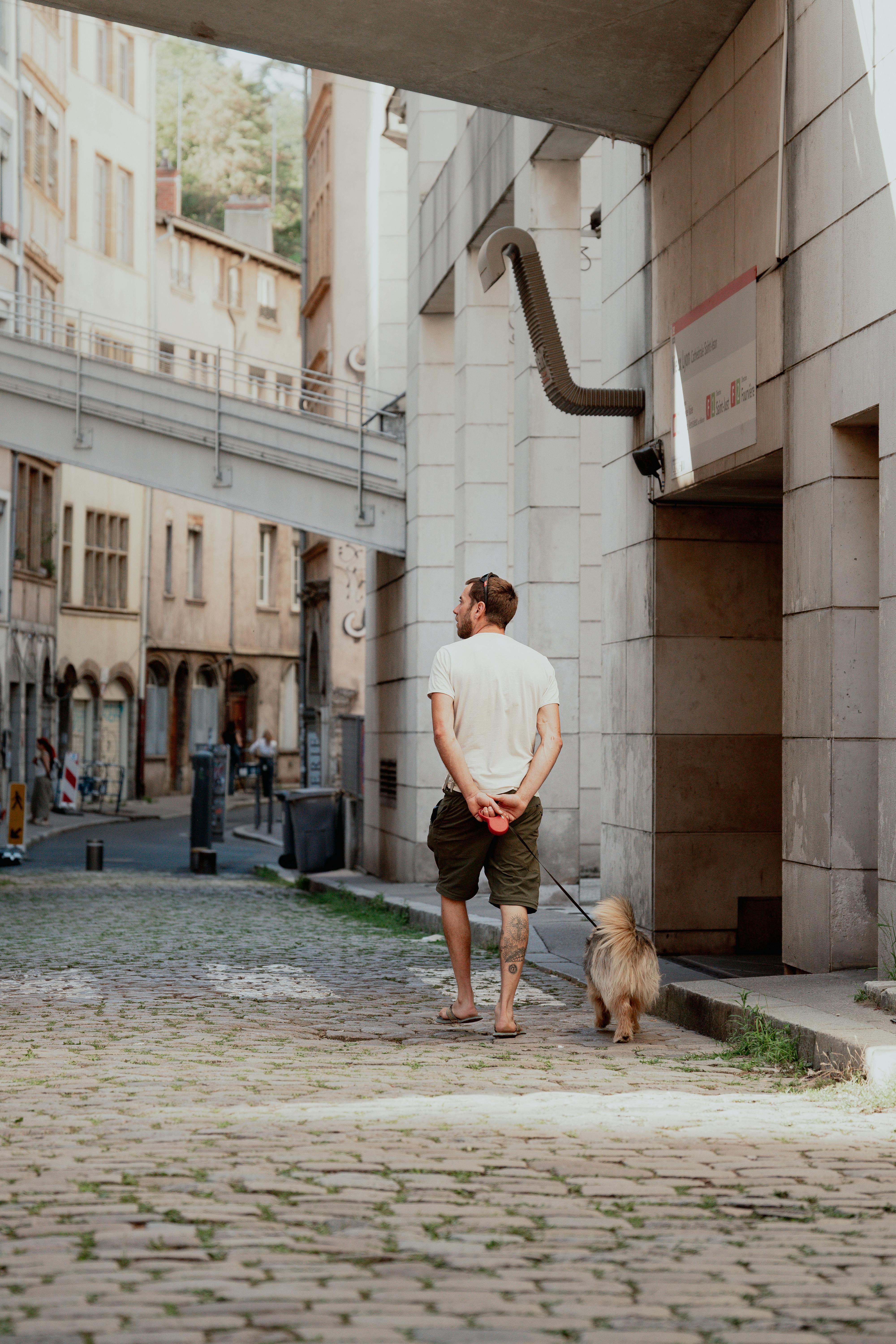 A man walking his dog down a narrow alley