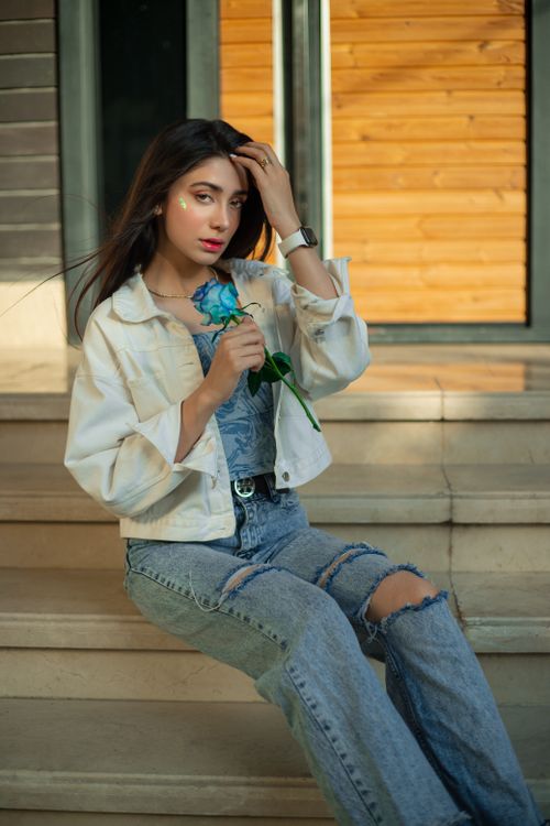 Free Fashionable young woman in denim with blue rose, sitting outdoors on steps. Stock Photo