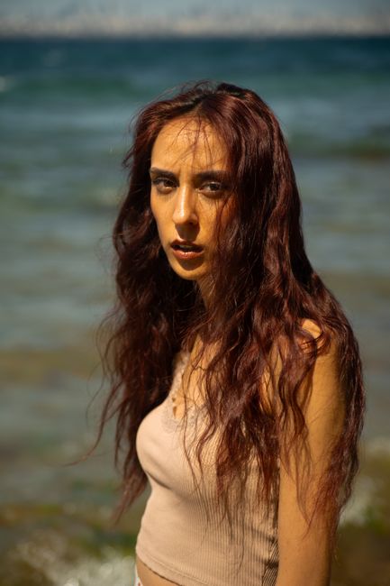 2026 Yaz Etek Modası: Trendler, Kombinler ve Stil İpuçları 5 A woman with long hair stands by the sea under the sun, exuding summer vibes and natural beauty.