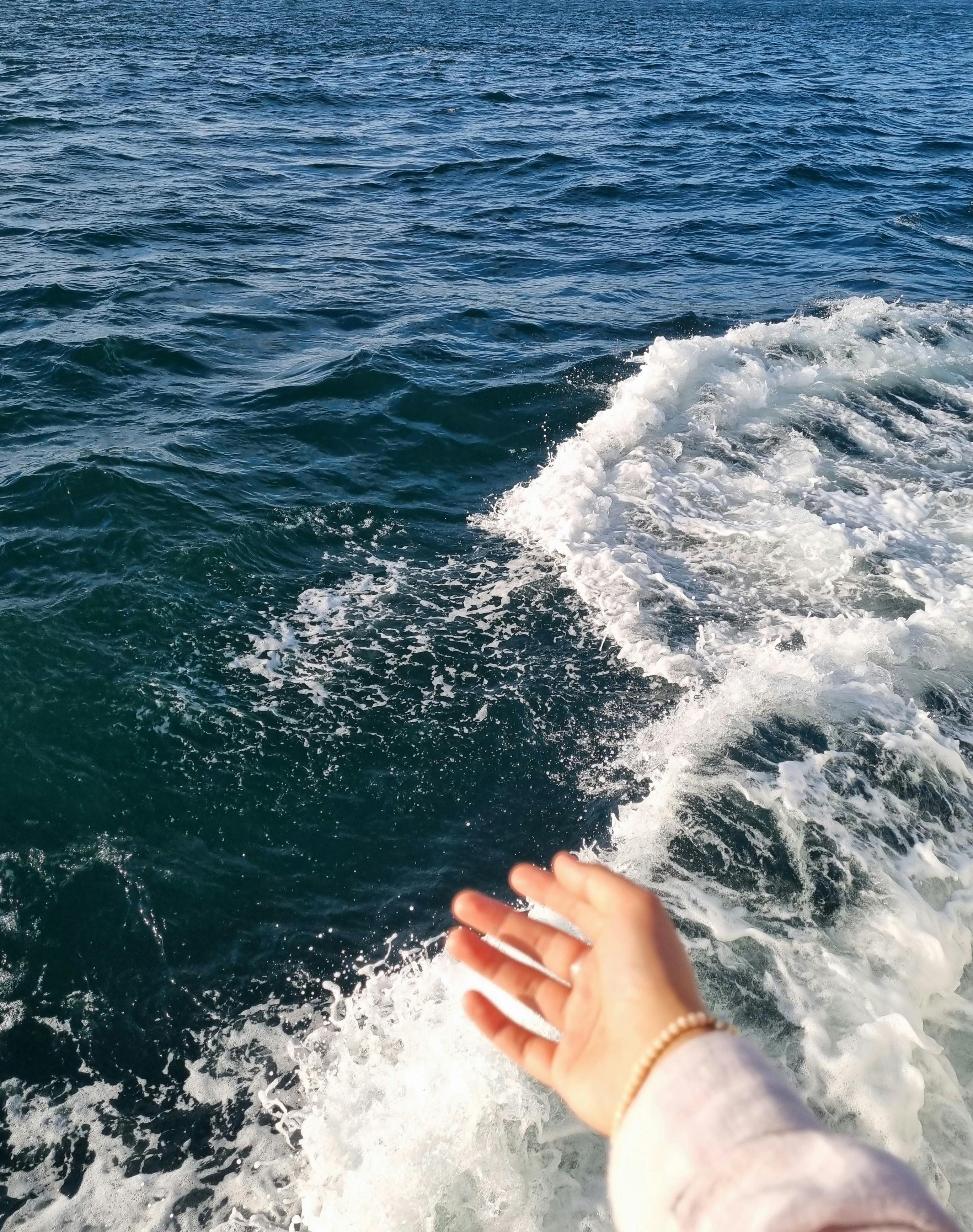 A hand reaches out over the rolling waves of the ocean near İstanbul.