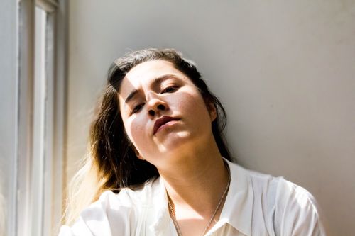 Free Serene portrait of a woman in natural sunlight by a window in Singapore. Stock Photo