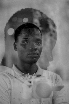Black and white artistic double exposure portrait of a thoughtful young man.