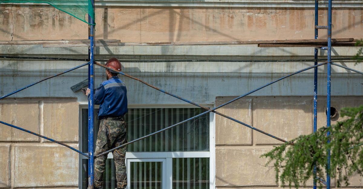Handwerker saniert eine Gebäudefassade auf einem Gerüst
