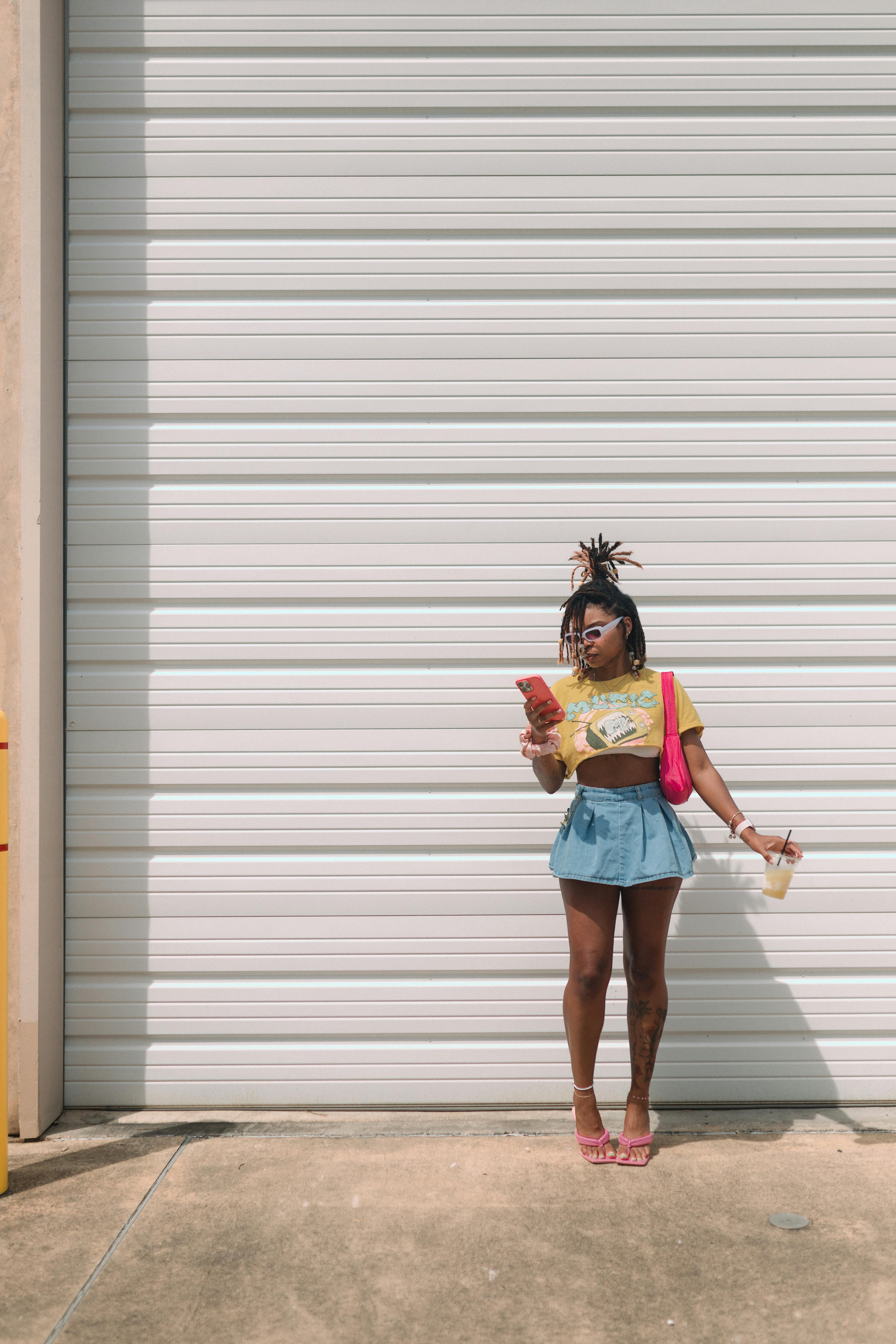 model in cropped top and mini posing with smartphone