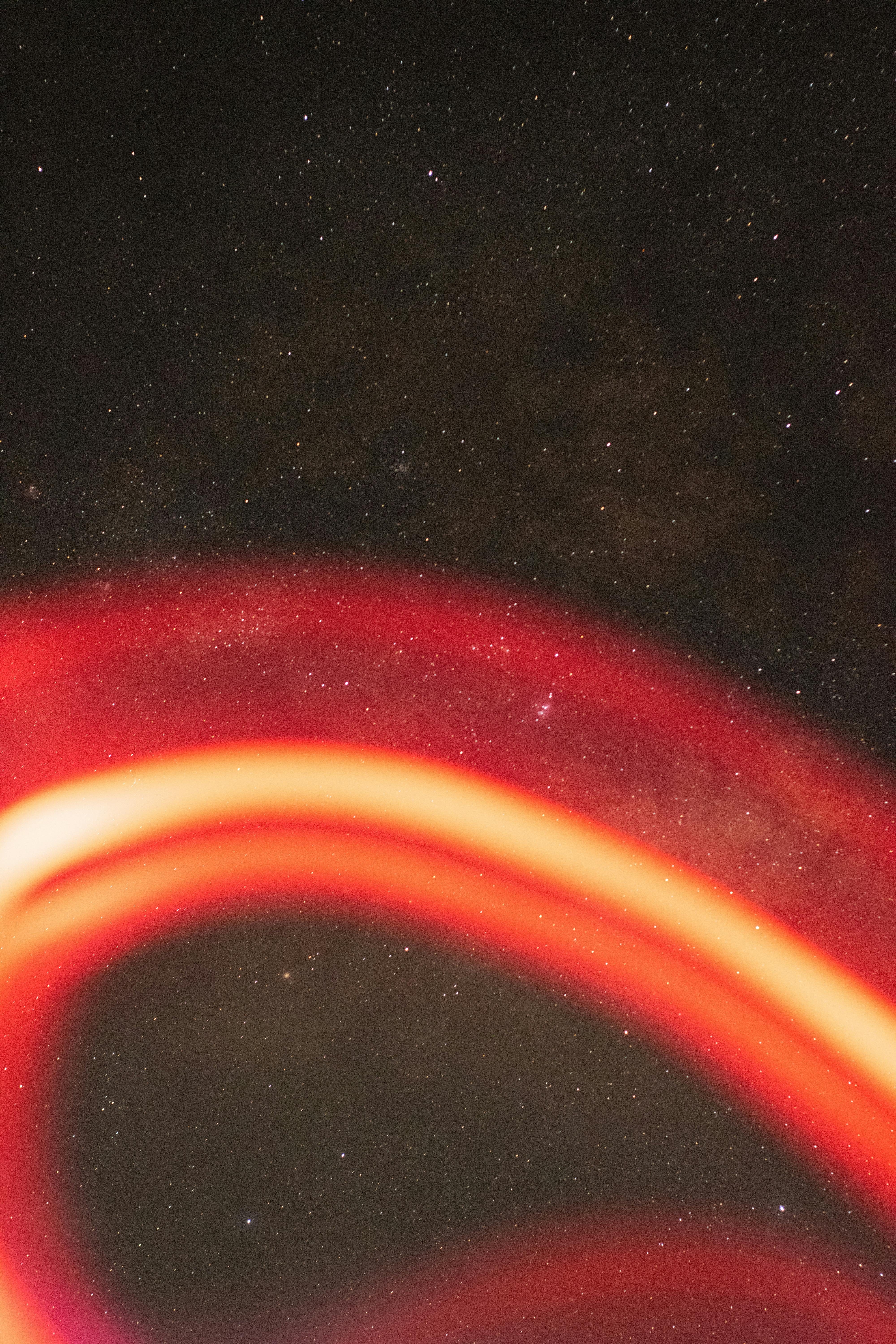 a blurry red light streak on the background of a starry night sky