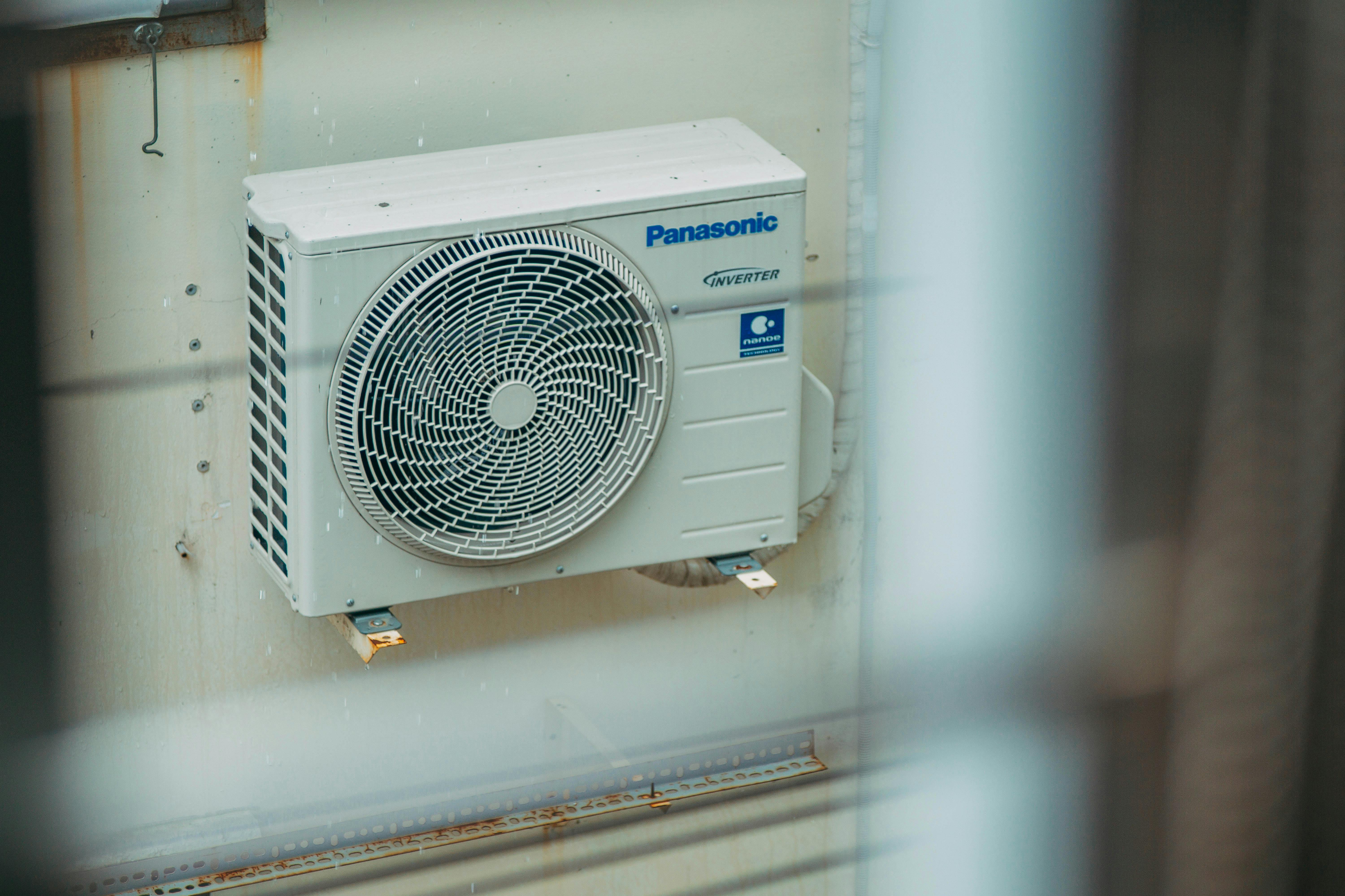 Air conditioner unit mounted outdoors on a building wall, showcasing modern HVAC technology.