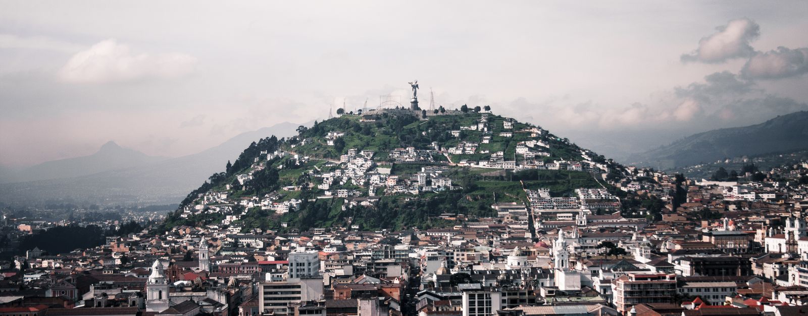 Aerial view of Quito featuring Panecillo Hill and Virgin statue, capturing historic architecture and vibrant cityscape.