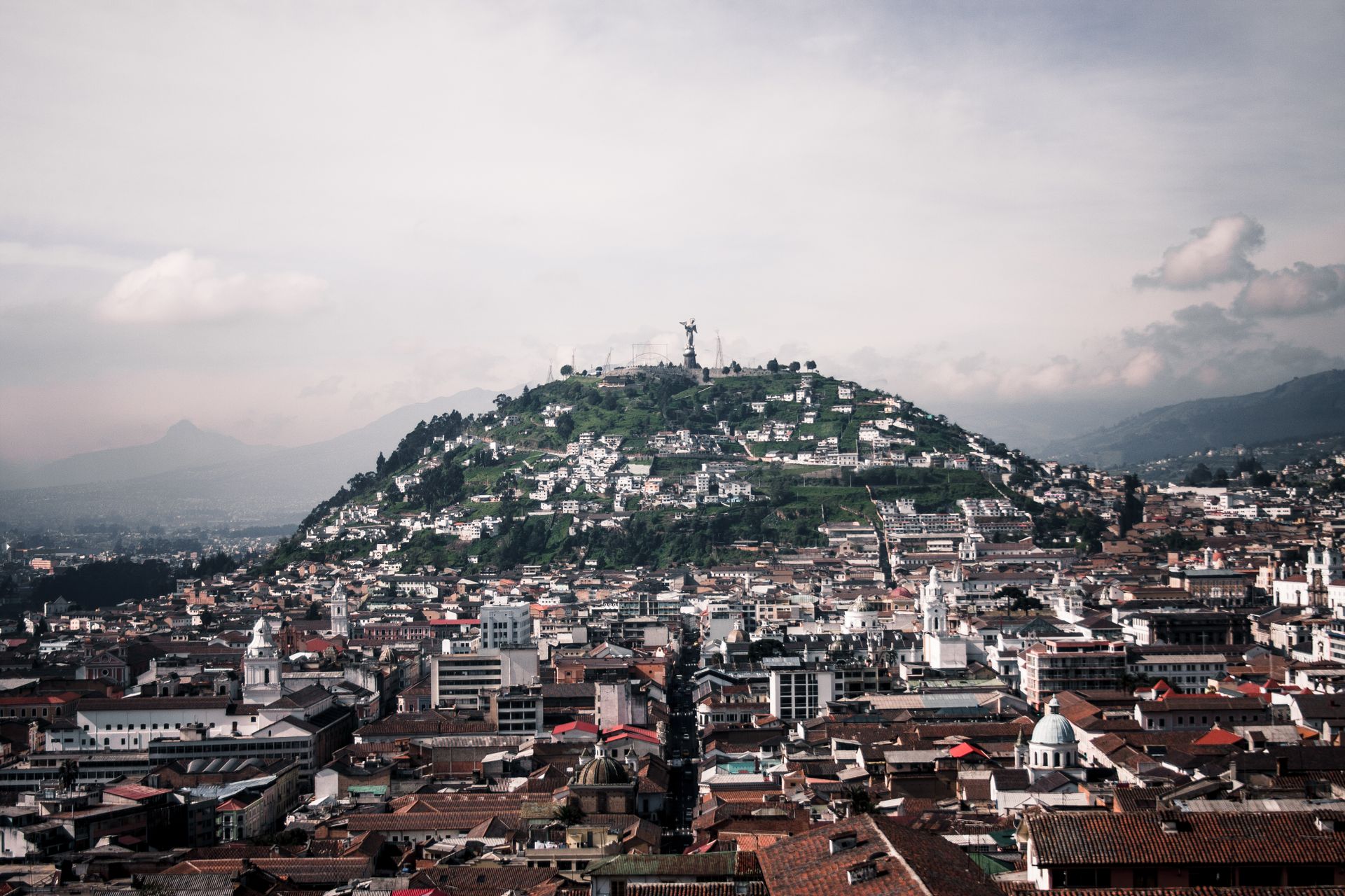 Aerial view of Quito featuring Panecillo Hill and Virgin statue, capturing historic architecture and vibrant cityscape.