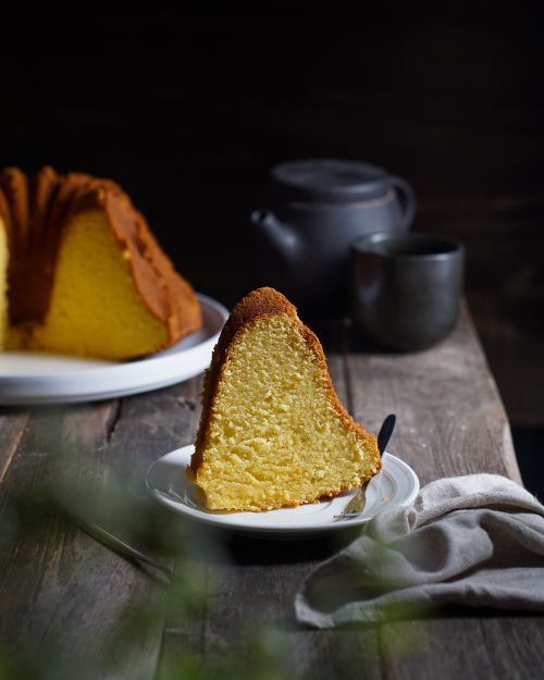 Free A mouthwatering slice of bundt cake on a wooden table with tea. Stock Photo