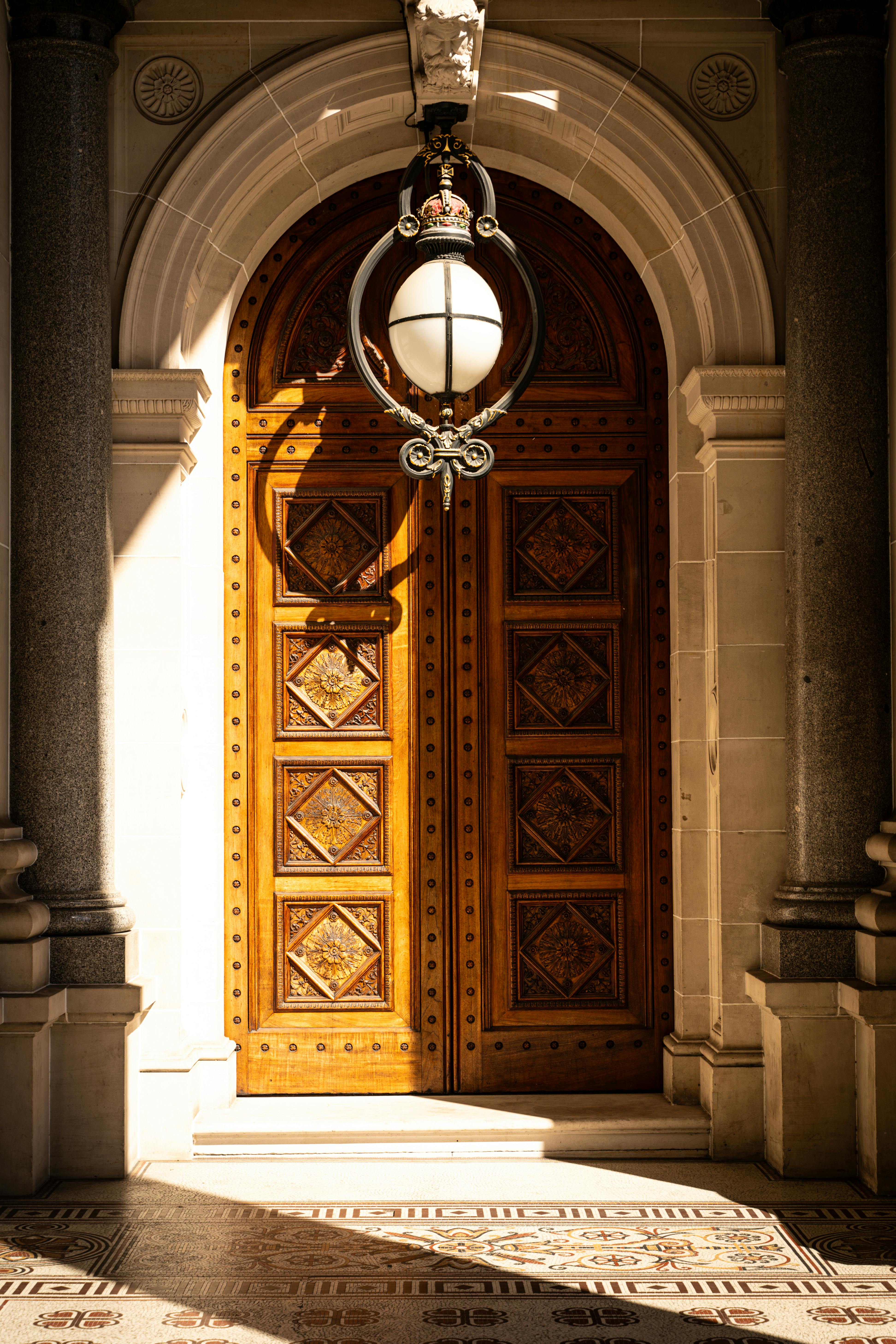 Elegant ornate wooden door in sunlight, showcasing classic architectural style.