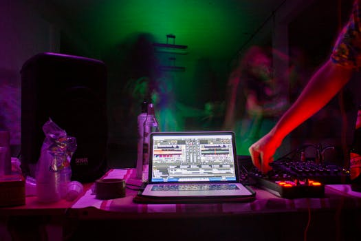 A lively nightclub scene featuring a DJ setup with colorful lighting and a laptop displaying music software.