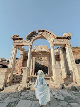 Visitor in white dress explores the ancient Roman Temple of Hadrian in Ephesus, Türkiye.