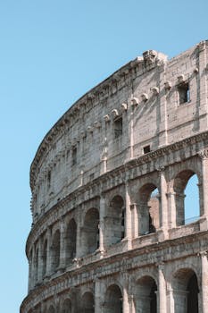 Stunning vertical shot of the Colosseum in Rome, capturing its majestic architecture against a clear blue sky.