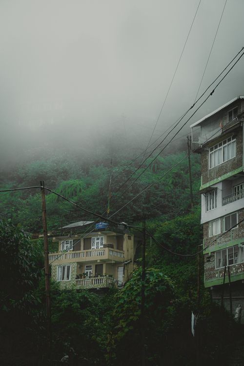 Free A foggy day in a mountain town nestled among lush greenery, capturing atmospheric weather and rustic architecture. Stock Photo