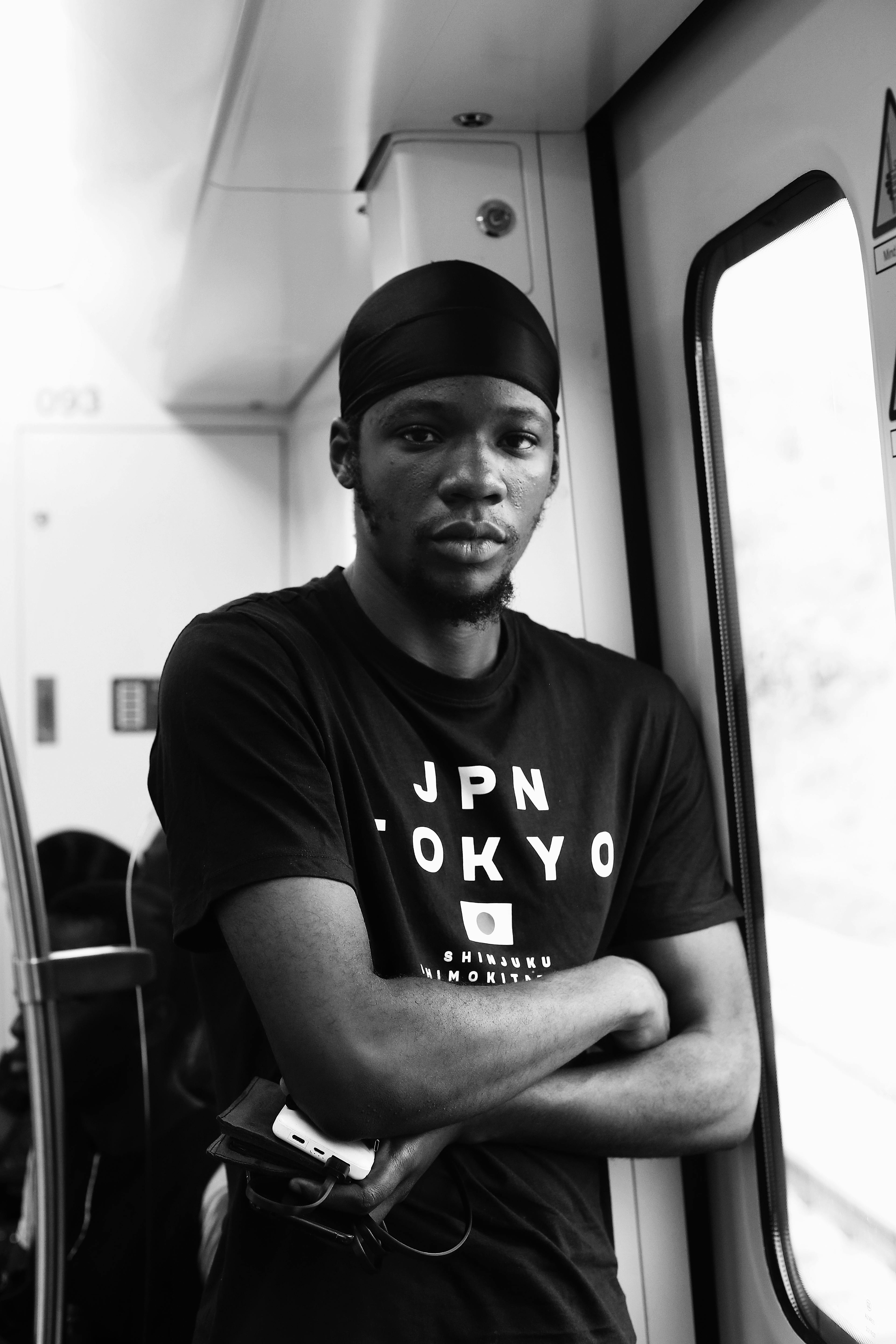 Black and white portrait of a serious man posing inside a train in Abuja, Nigeria.