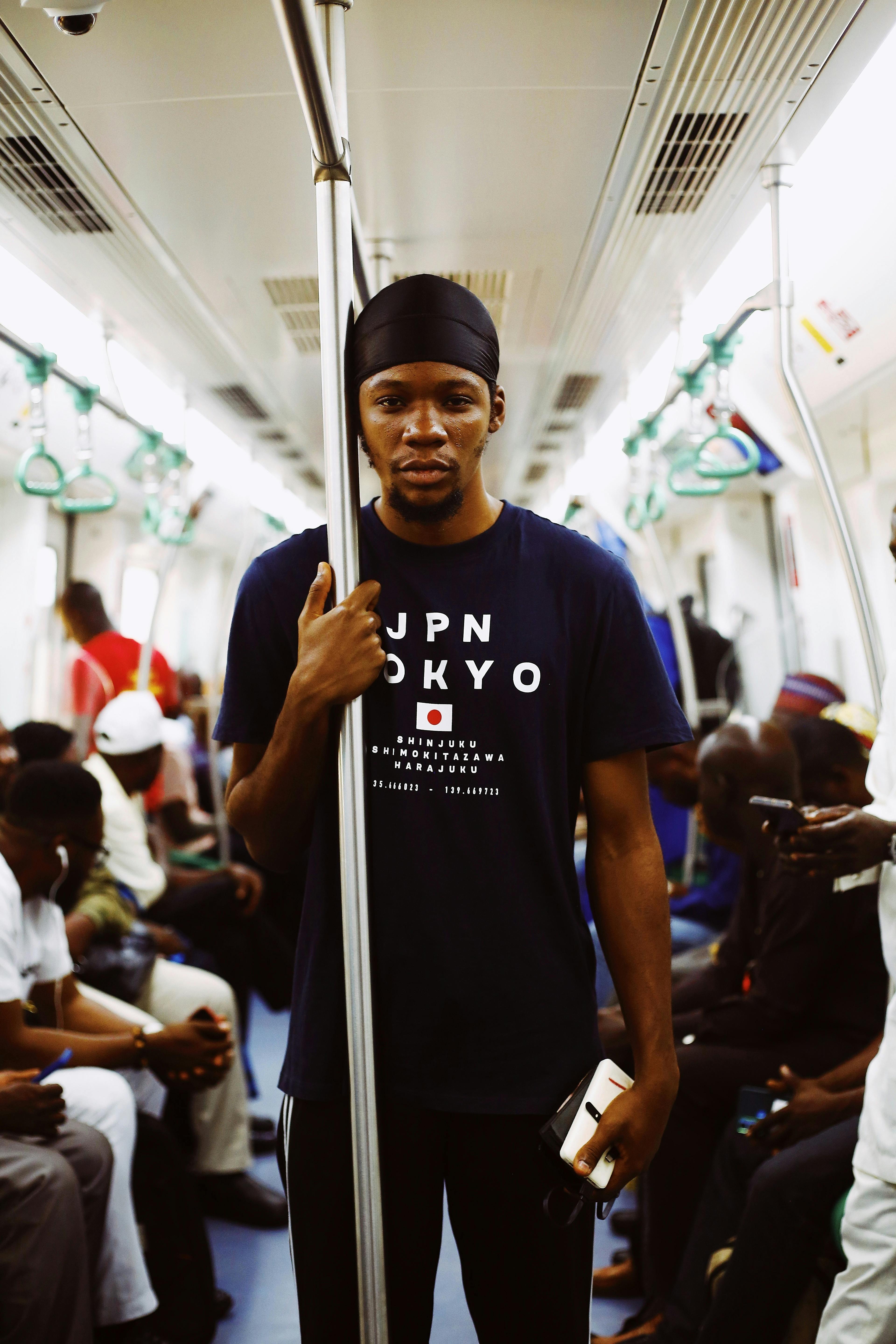 young man travelling on a subway train with a phone in his hand