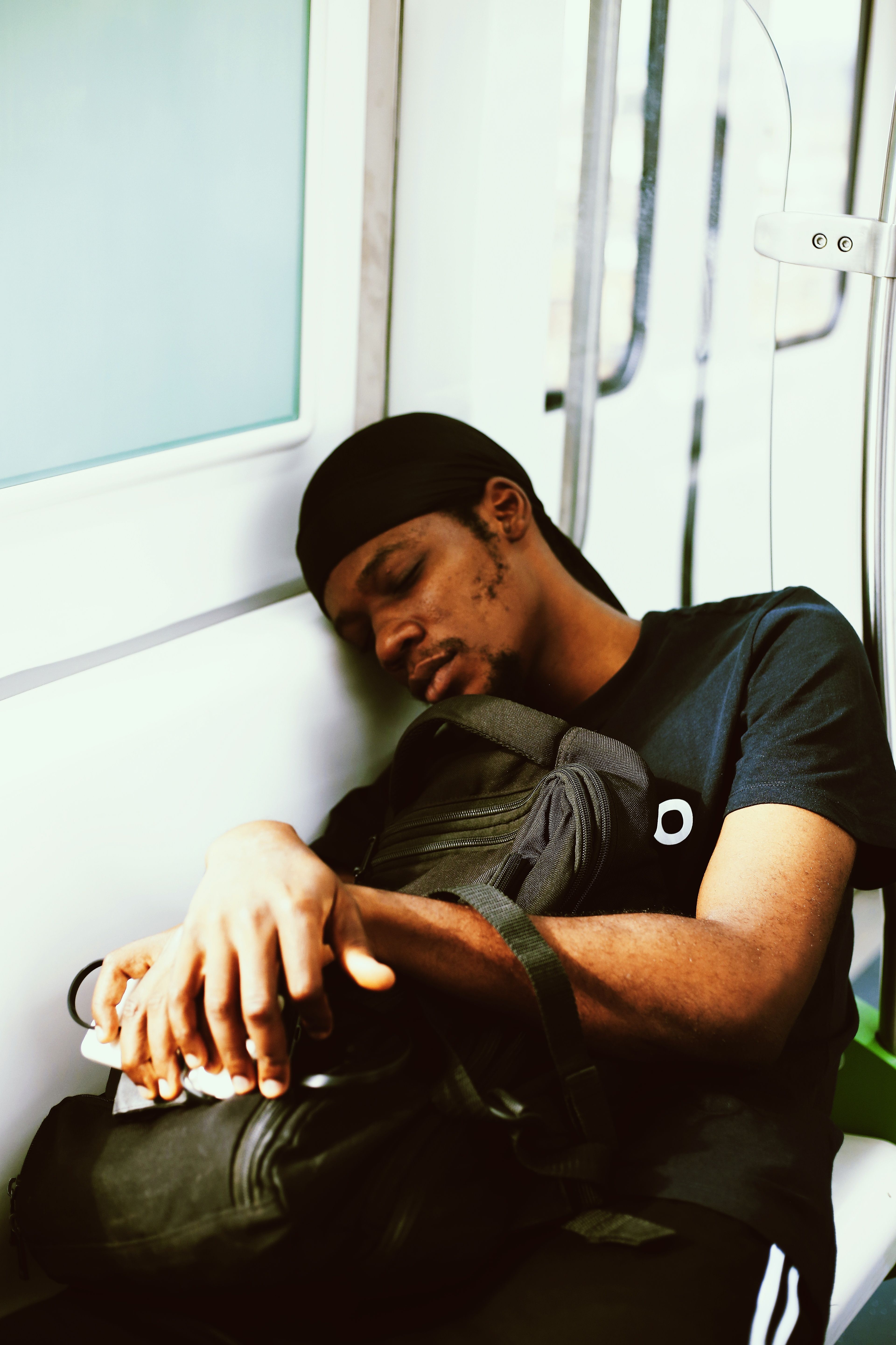 A young man takes a nap while holding his backpack on a train in Abuja, Nigeria.