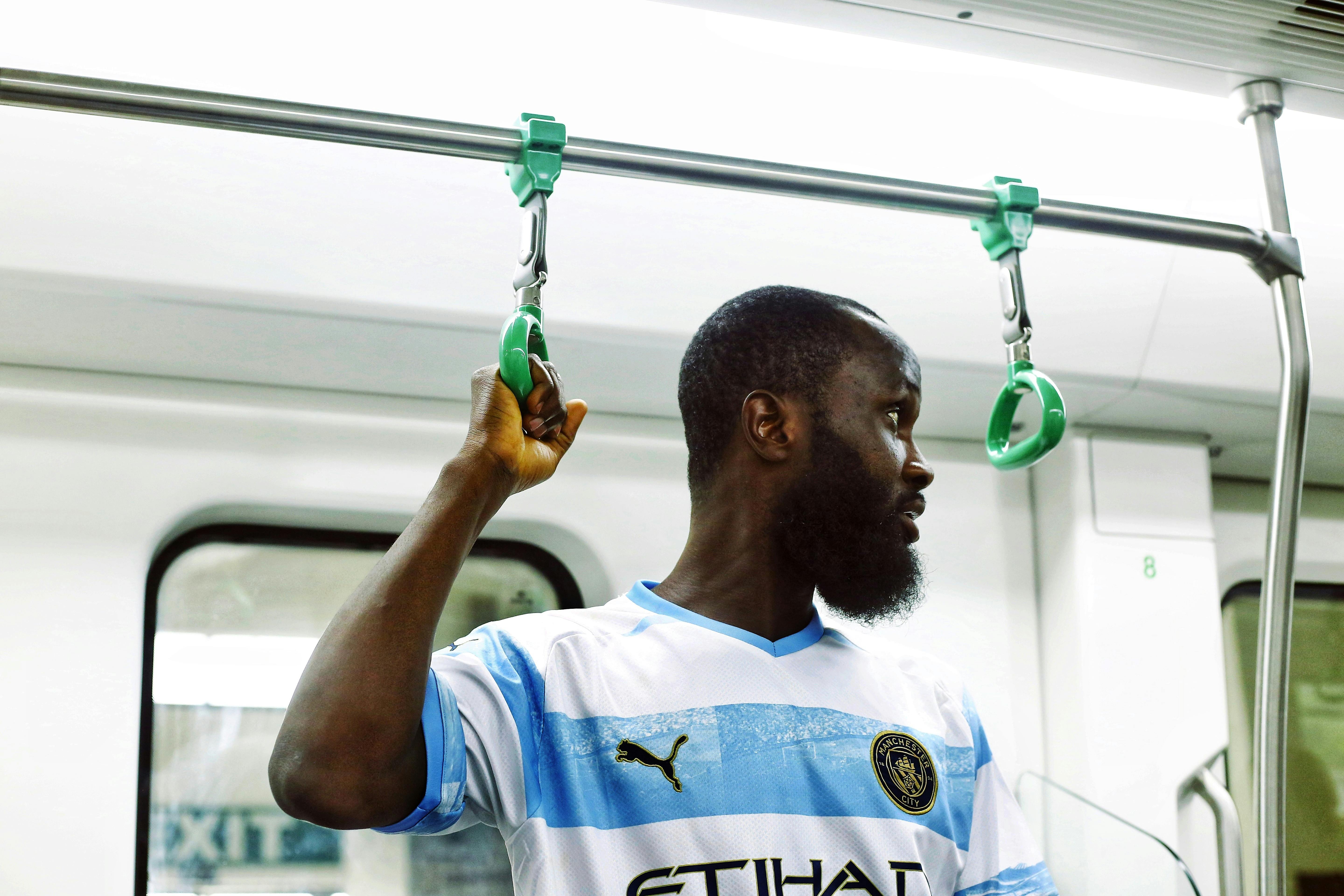 African man holding onto handrail inside a metro train, capturing urban lifestyle in Abuja.