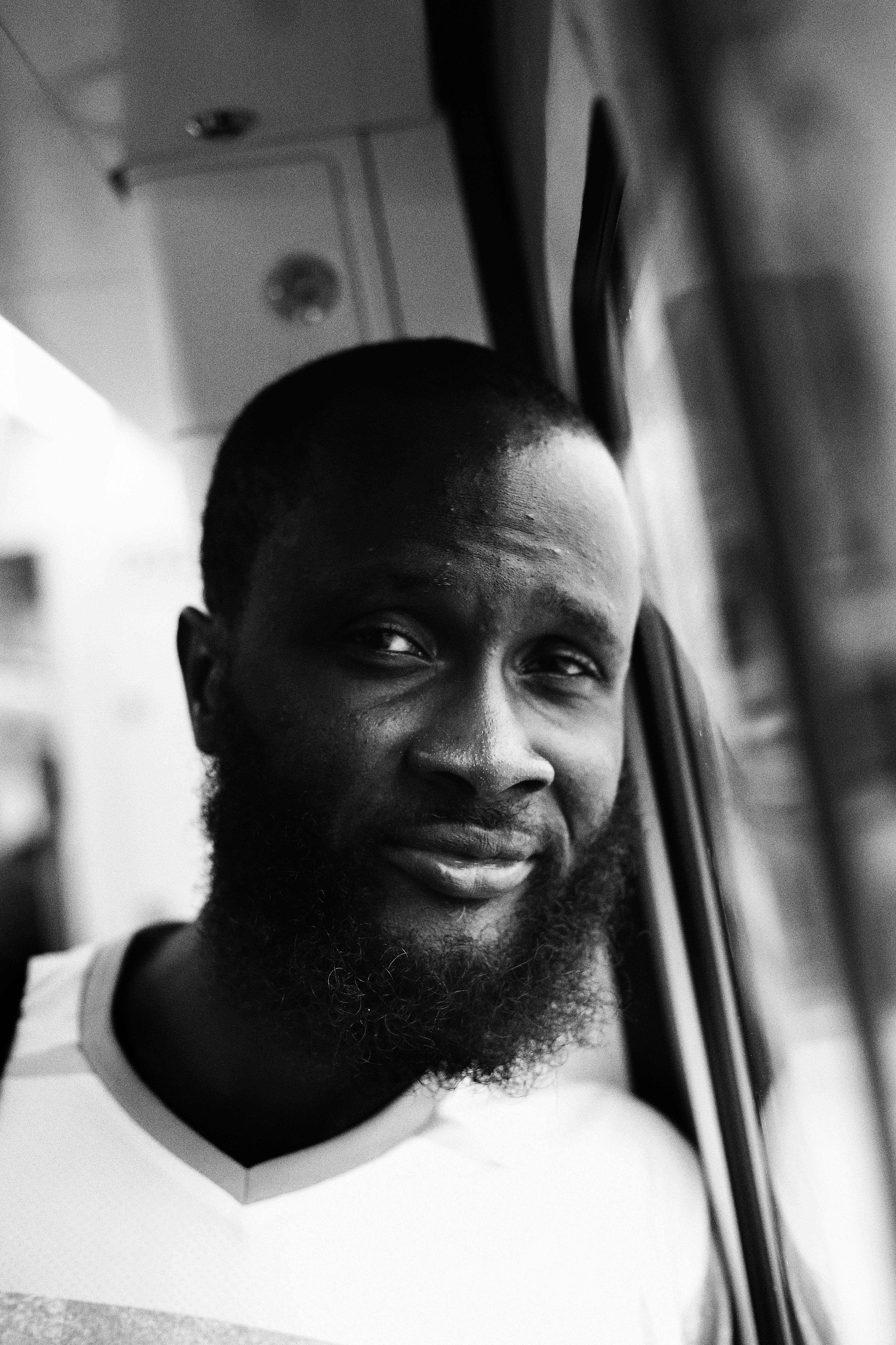 Close-up black and white portrait of a man gazing thoughtfully through a window.