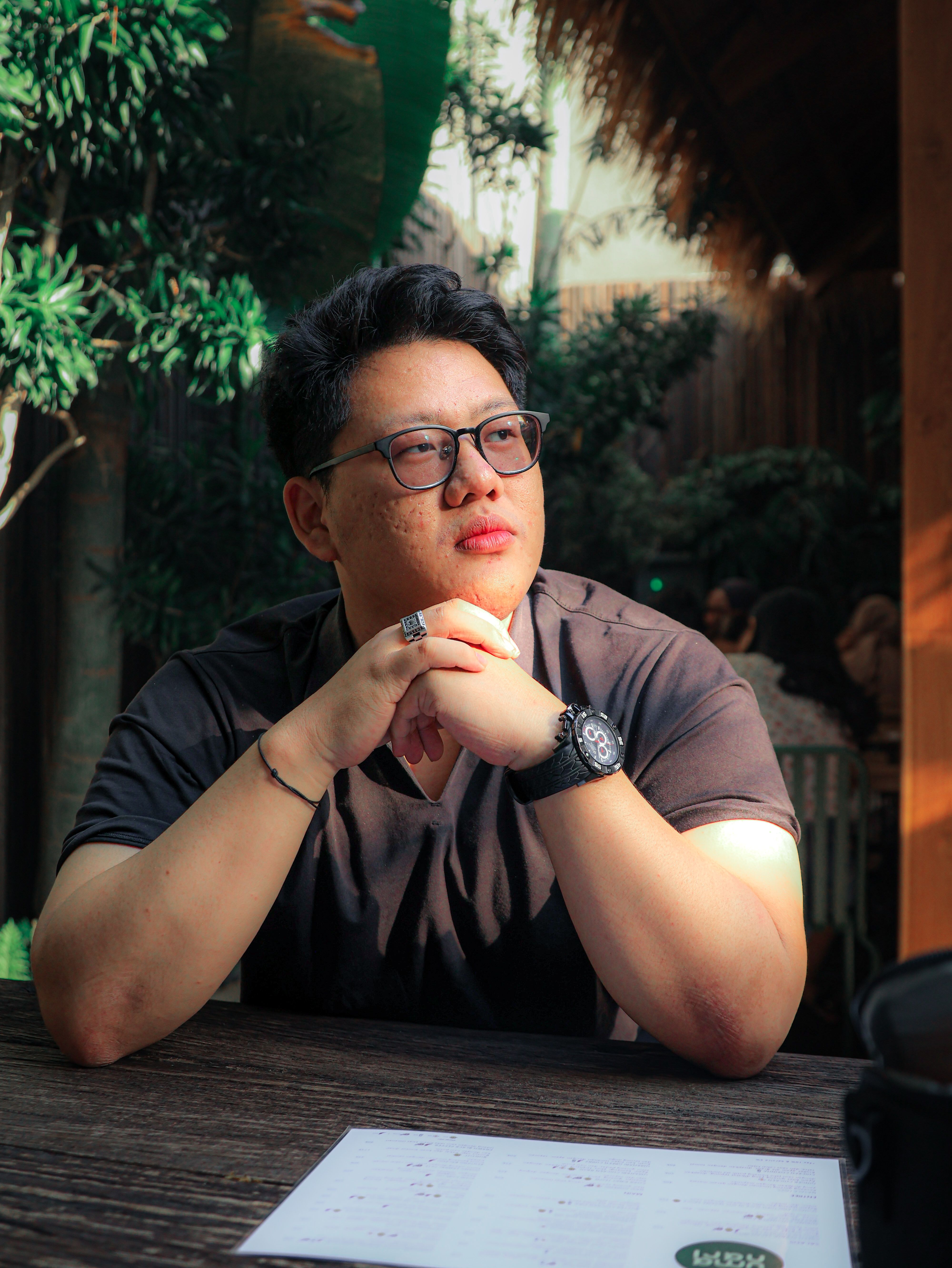 A thoughtful man enjoying sunlight at a café, depicting relaxation and contemplation.