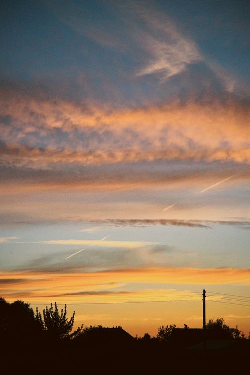 Free Vibrant sunset with clouds silhouetted over Poznań, Poland, showcasing a dramatic evening sky. Stock Photo