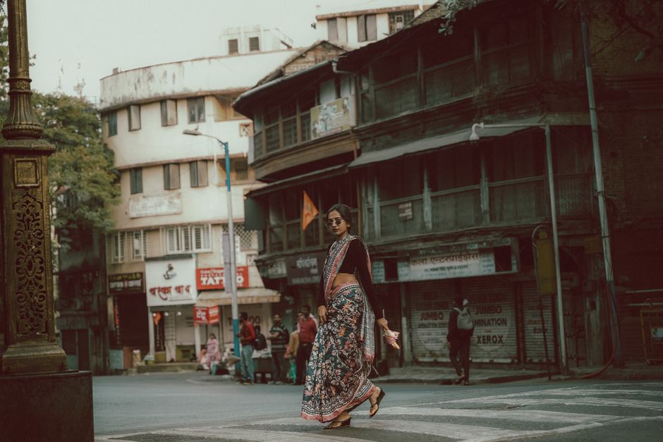 An elegant woman in traditional Indian saree walking on a historical street in Pune, India.