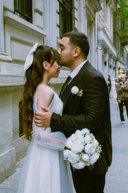 Bride and groom share a romantic kiss outdoors on a cobblestone street, capturing the essence of love and marriage.