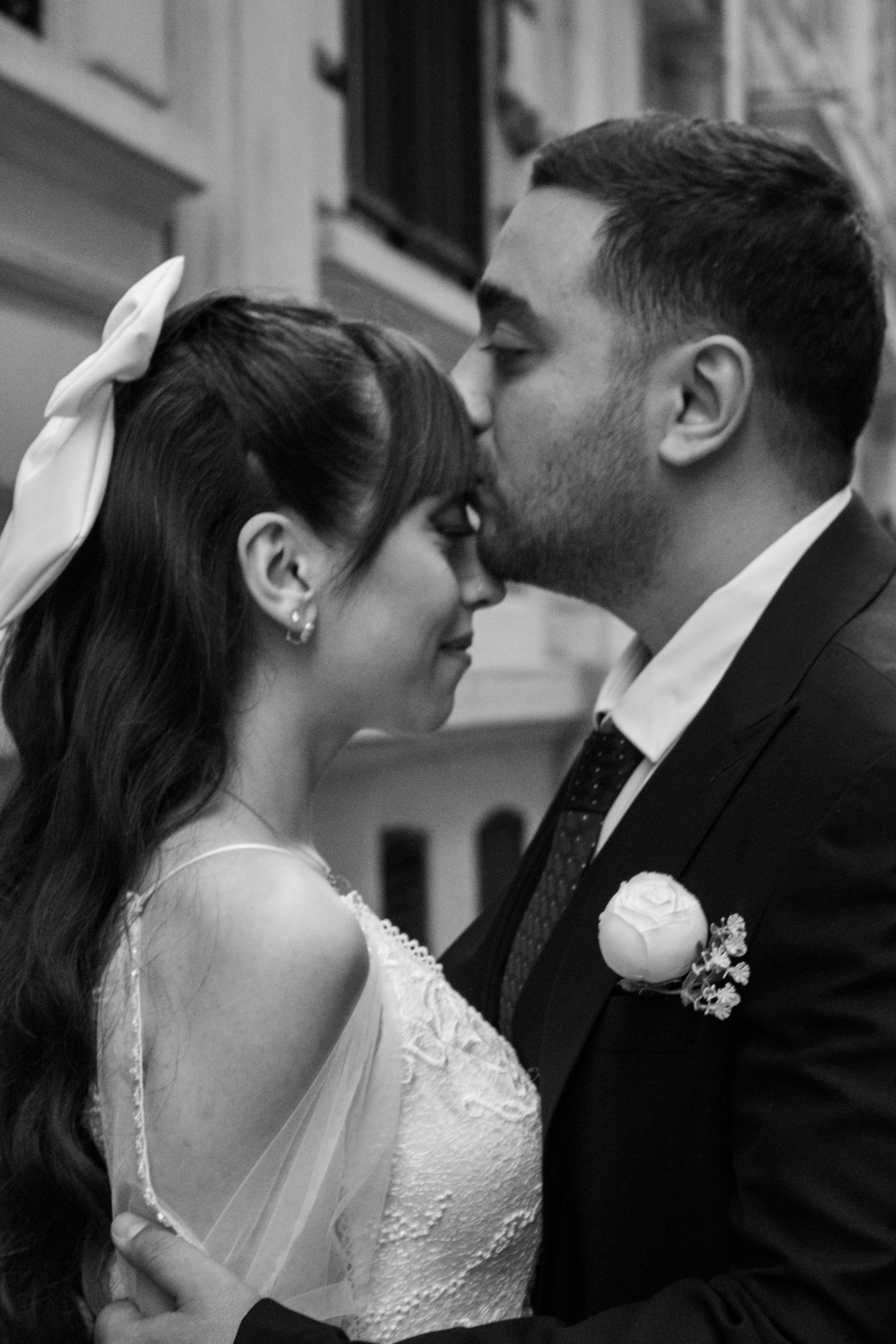 A tender moment between a bride and groom captured in black and white during an outdoor photoshoot.