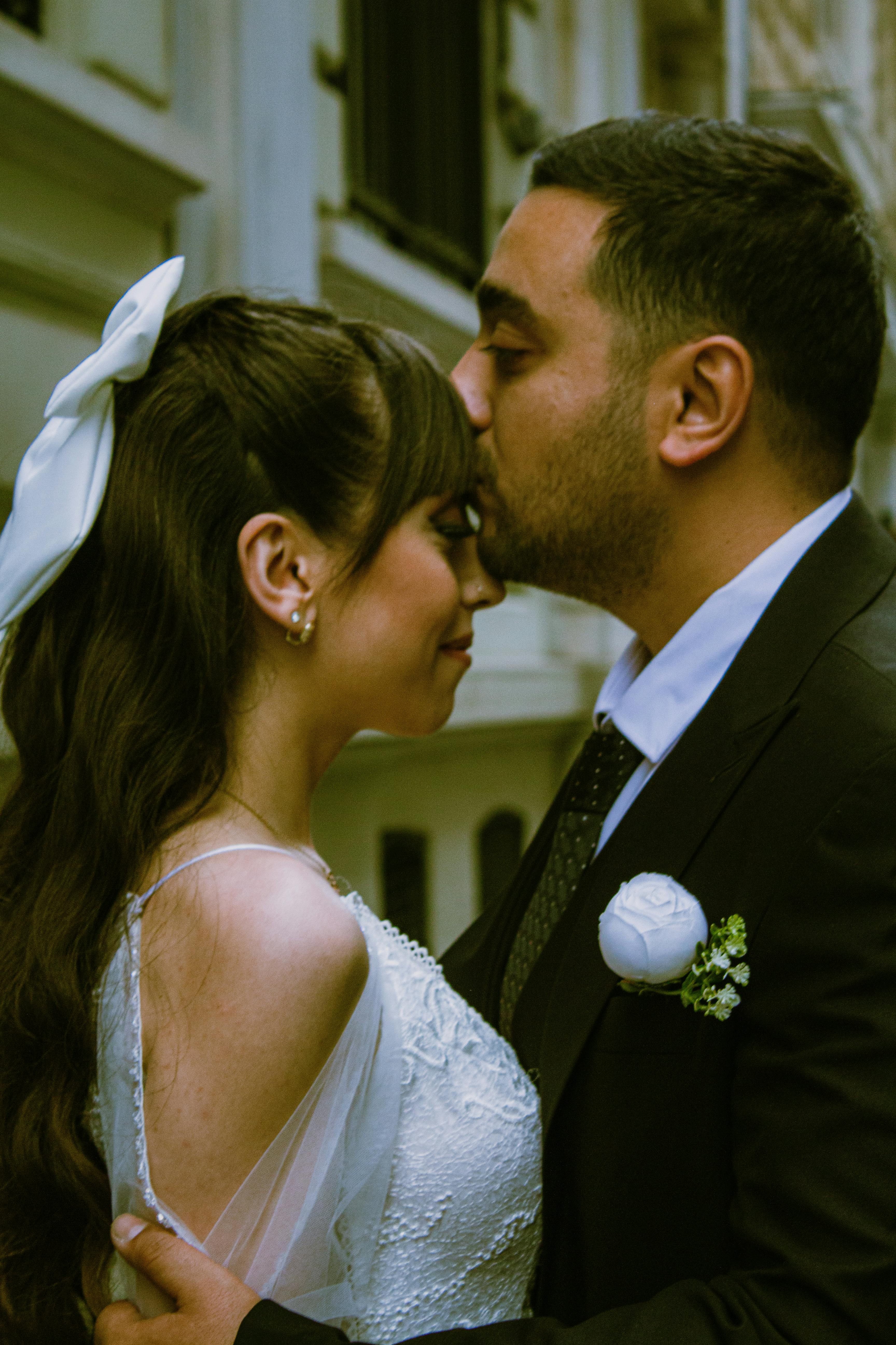 A touching moment between a bride and groom sharing an intimate kiss outdoors.