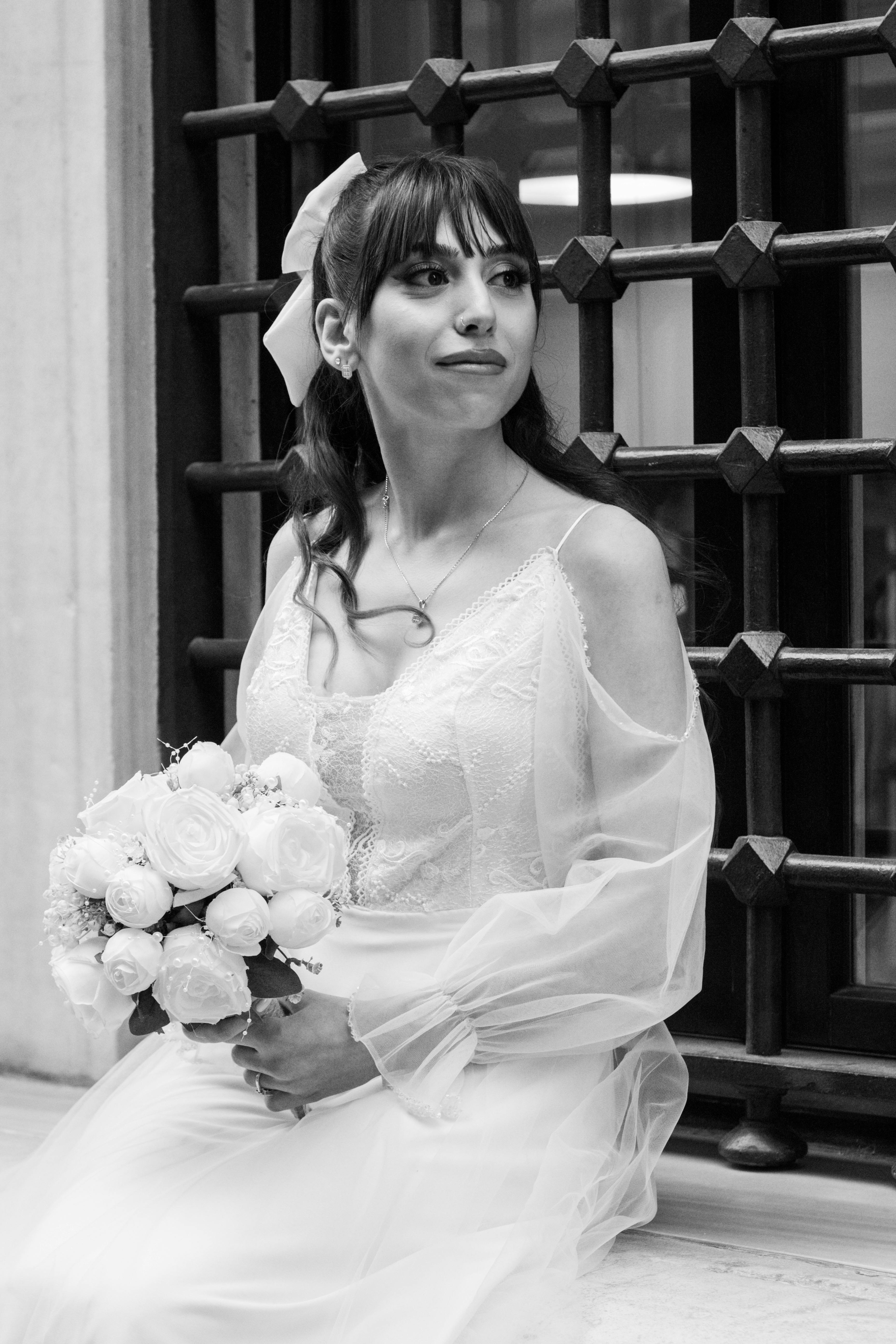 Beautiful bride in lace dress, holding a bouquet, urban background.
