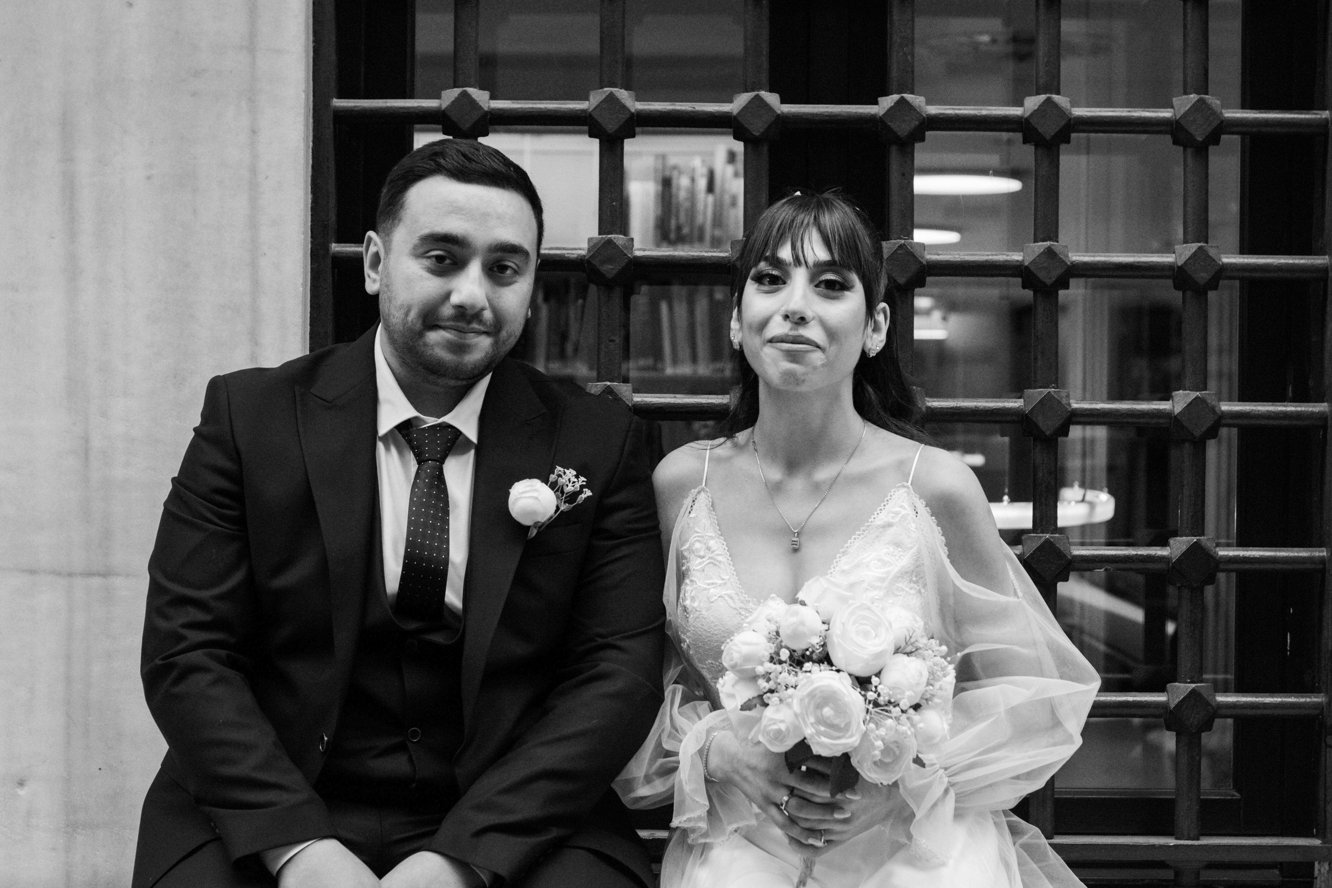 Classic black and white portrait of a bride and groom seated together, showcasing elegance.