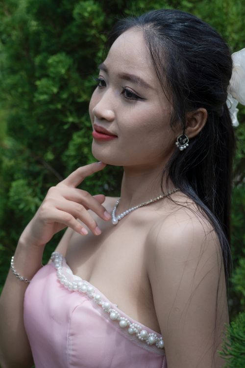 Free Portrait of a woman in elegant bridal attire, captured outdoors with greenery. Stock Photo