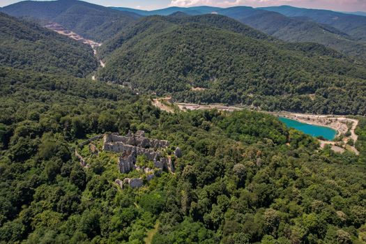 Stunning aerial shot of ancient ruins in Orahovica, Croatia, surrounded by lush forests and a serene lake.