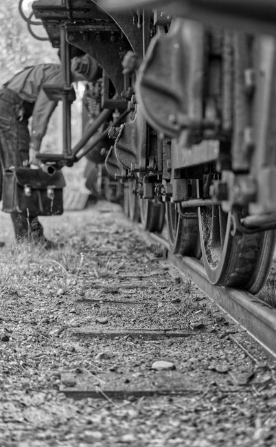 Fotomural Fotografía en blanco y negro de un tren vintage y un ingeniero realizando mantenimiento en las vías.