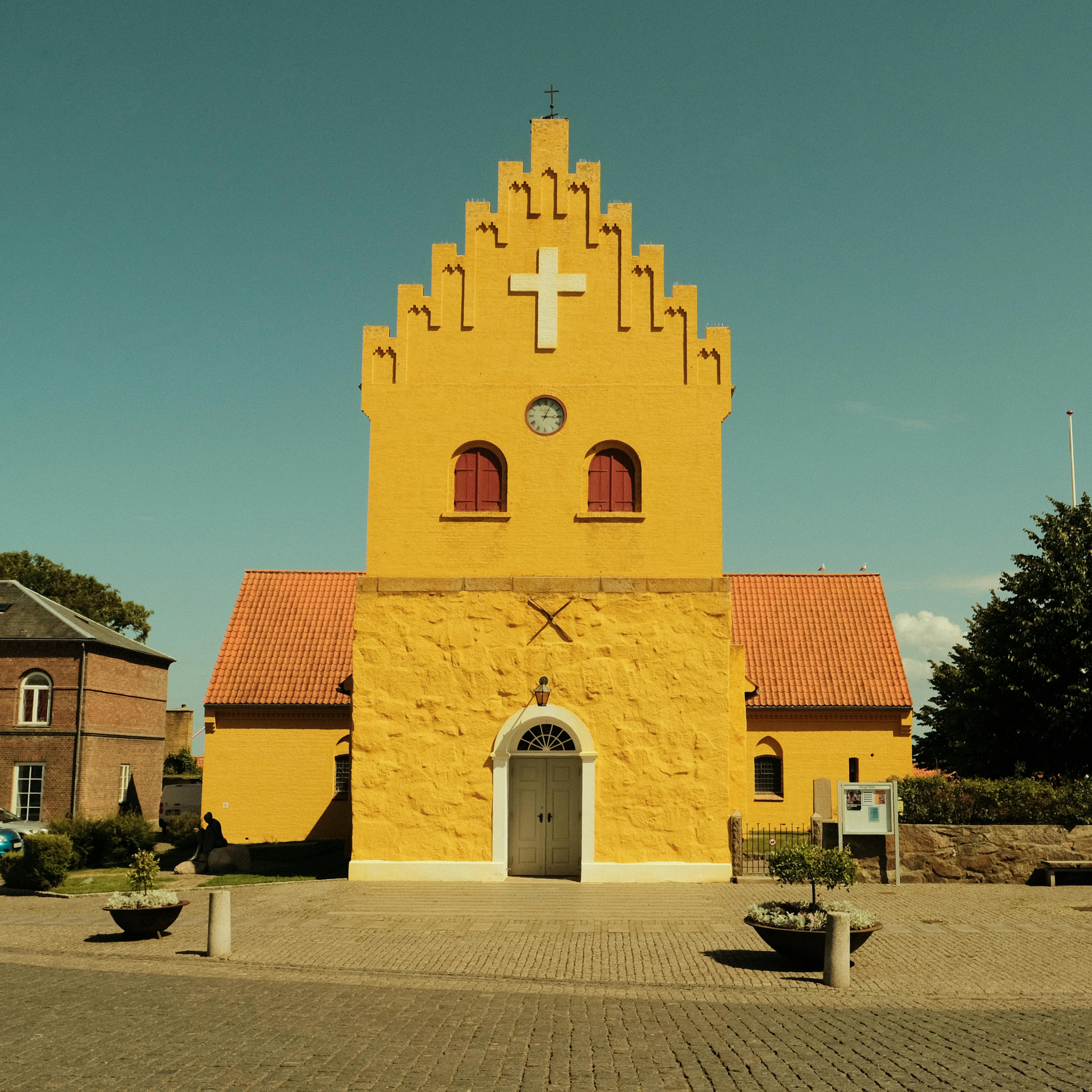 Bright yellow church facade with characteristic stepped gable, showcasing Gothic revival architecture.