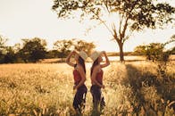 日落时分，两名穿着相似服装和帽子的妇女在乡村田野里摆姿势