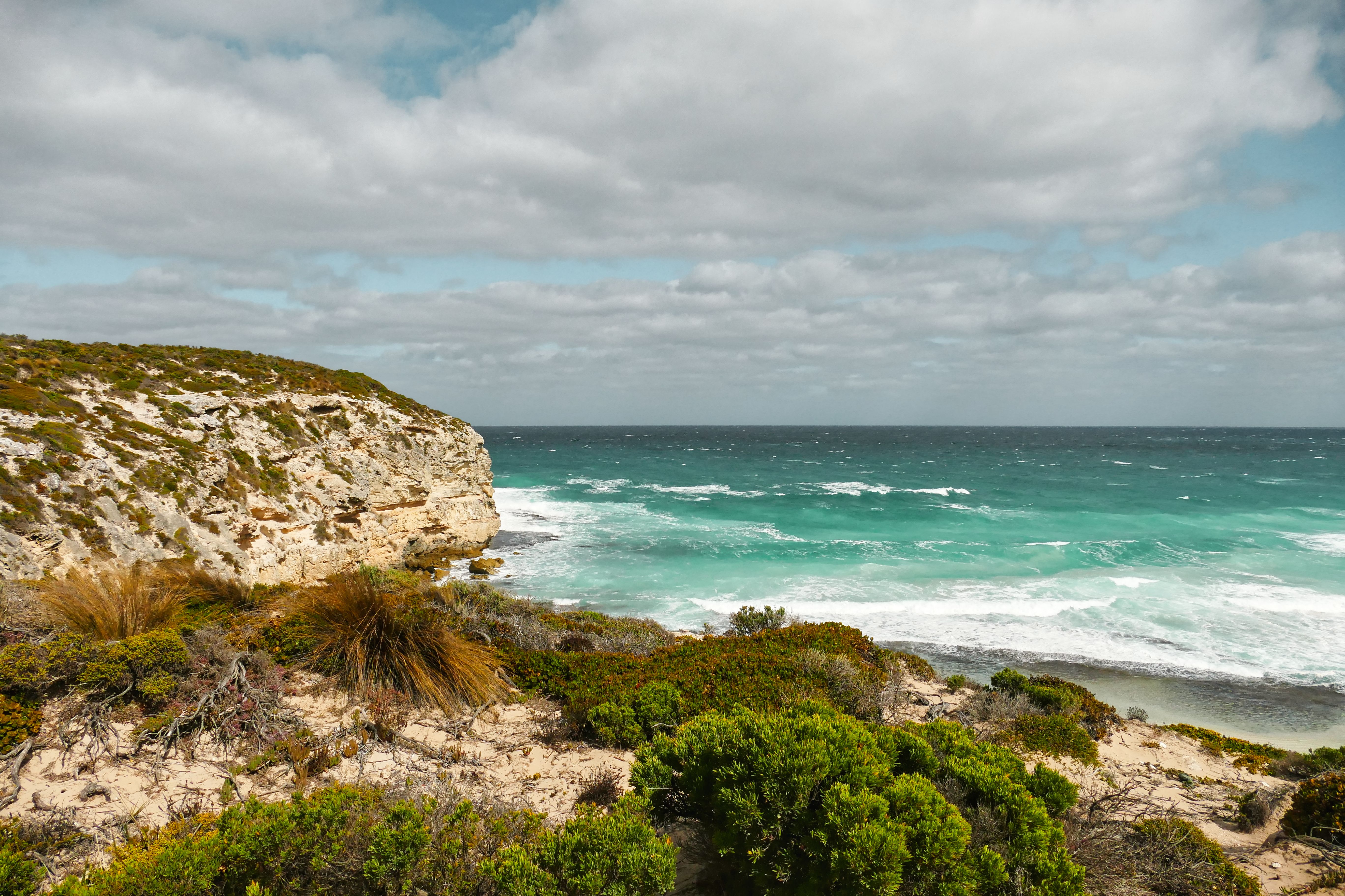Explore the rugged cliffs and vibrant turquoise waves at Stokes Bay, Australia, captured on a sunny day.