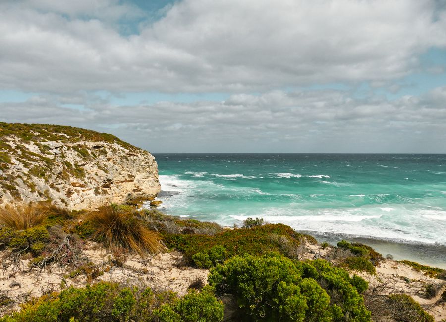 Explore the rugged cliffs and vibrant turquoise waves at Stokes Bay, Australia, captured on a sunny day.